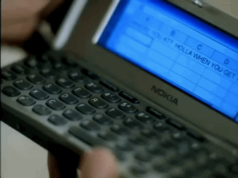 a clip from the music video for Nelly's Dilemma, picturing the message "WHERE YOU AT? HOLLA WHEN [YOU GET THIS.]" in cell A1 of an excel spreadsheet, loaded on a Nokia 9290 Communicator