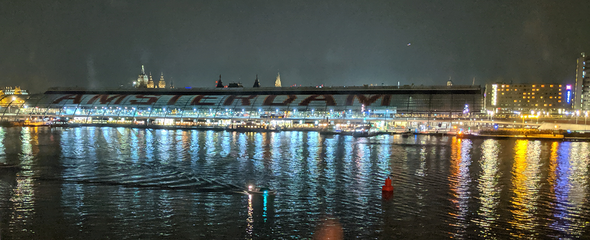Photograph of Amsterdam station at night reflecting on the water